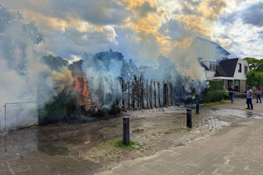 Bewoners blussen coniferenhaag met tuinslang